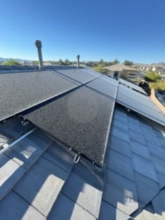 Dusty solar panels on shingle roof before professional cleaning